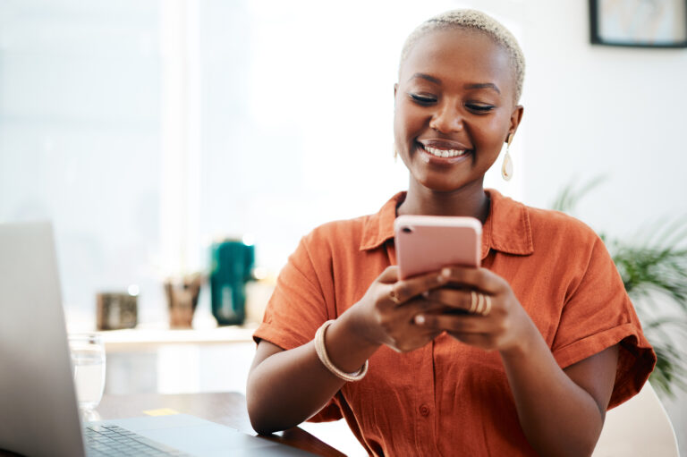Online, business and black woman at desk with mobile for communication, texting or social network. Digital, media agency and employee with smile for typing, web post or browsing internet in office